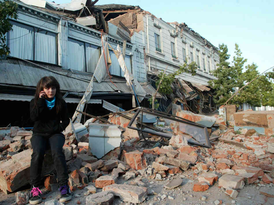 A resident sits on the debris of a collapsed house in the city of Talca, some 275 kilometers south o A resident sits on the debris of a collapsed house in the city of Talca, some 275 kilometers south o