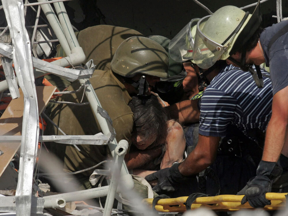 Rescue workers pull out of the rubble an earthquake survivor in Concepcion, southern Chile, Saturday
