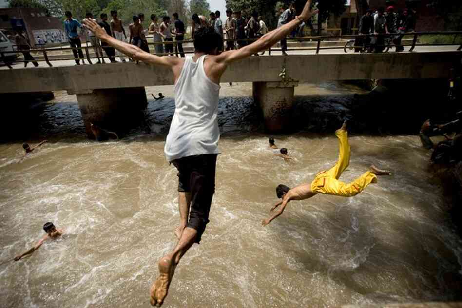 Pakistani men jump into a water canal to take a reprieve from the heat in Lahore, Pakistan, on Sunda