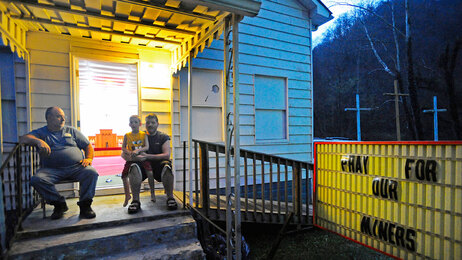 Billy Pettry, Caden Gray, 5, and Brandon Gray, from left, sit on the steps of the Marsh Fork Worship Center in Eunice, W.Va., near the entrance to Massey Energy's Upper Big Branch Coal Mine Monday, April 5, 2010 in Montcoal, W.Va. Pettry a retired coal miner of 20 years who said he is on disability with black lung says,