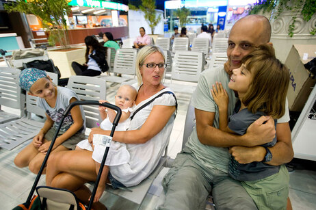 James Bader, right, hugs his daugher, Nancy Bader , 8, as his wife, Ursula Allison holds daughter, Johanne Bader, 1, while daughter Lily Bader watches as they wait for a flight at Bangkok International Suvarnabhumi Airport April 27, 2010. The Bader family from London had been on holiday in Thailand and was supposed to return to the United Kingdom on a flight from Bangkok on April 21st but had their flight cancelled due to the eruption of the Eyjafjallajokull volcano in Iceland. They were able to secure seats on a flight on April 28. (Photo by Andy Nelson /Getty Images)