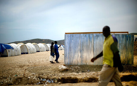 A man walks past the tin walls of an outdoor latrine at Camp Corail, in Croiz de Bouquets outside of Port-au-Prince, Haiti, on Tuesday May 4, 2010. Internally displaced people living in makeshift camps in the city were moved to the Corail camp in an attempt to give them a safer and more permanent living situation. January's devastating earthquake has left hundreds of thousands of people homeless most which are still within in the city limits of Port-au-Prince. (David Gilkey/NPR)