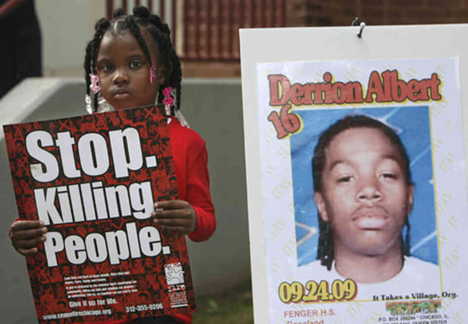 Nadashia Thomas, 6, a cousin of Derrion Albert, holds a sign beside a poster of Derrion Albert at Fe Nadashia Thomas, 6, a cousin of Derrion Albert, holds a sign beside a poster of Derrion Albert at Fe