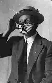 Old black and white photograph of a man in a suit wearing a flu mask. Old black and white photograph of a man in a suit wearing a flu mask.