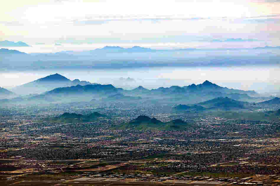 Smog settles between hills north of downtown Phoenix. In the Phoenix metropolitan area, the natural inversion layer traps rising particulates and forms "brown cloud" as the ground heats up during the day. Smog affects inhabitants of urban populations who already suffer from respiratory ailments, and continued suburban growth contributes to declining air quality.