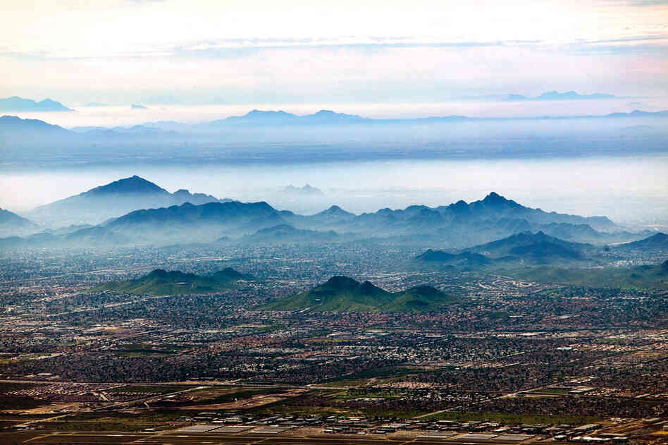 Smog settles between hills north of downtown Phoenix. In the Phoenix metropolitan area, the natural inversion layer traps rising particulates and forms "brown cloud" as the ground heats up during the day. Smog affects inhabitants of urban populations who already suffer from respiratory ailments, and continued suburban growth contributes to declining air quality.