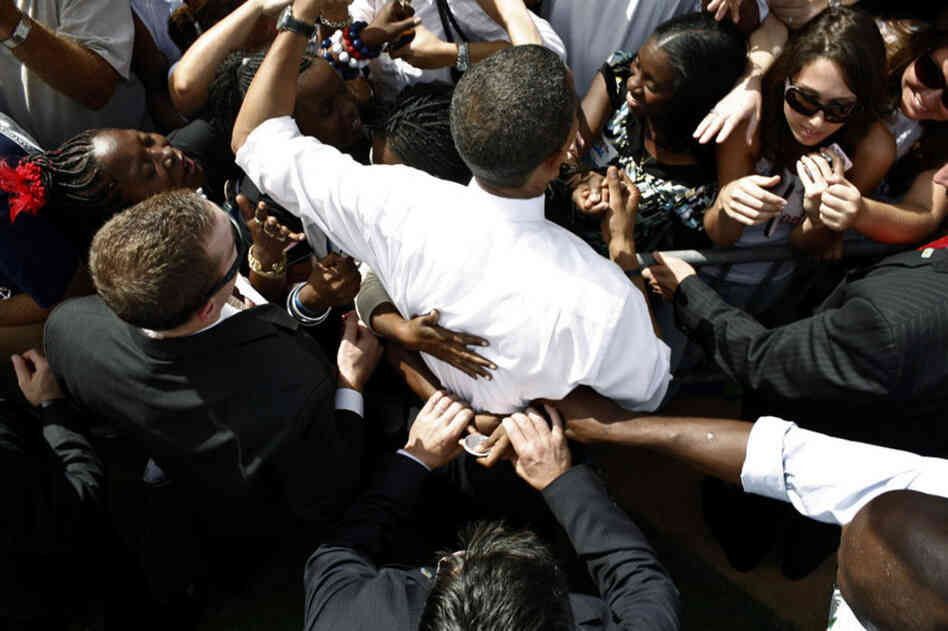 Secret Service agents tug at the hands of a supporter as she hugs Obama at Legends Field in Tampa, Fla.