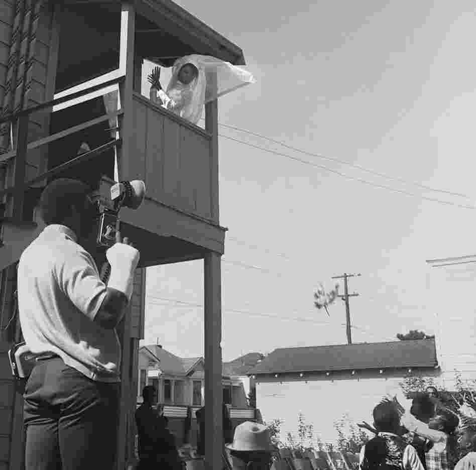 Bride throws bouquet, West Oakland, 1970.  By participating in neighborhood improvement efforts in Oakland, Leonard befriended many community members and photographed them often. 