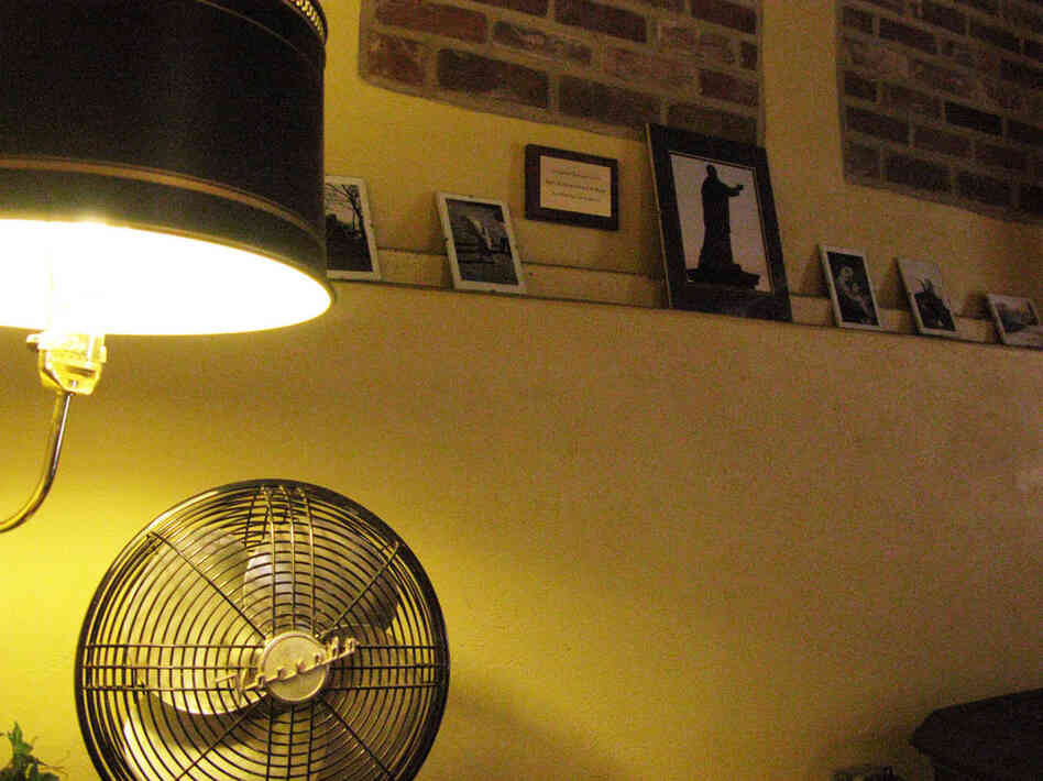 An antique fan on a desk in the Saint Vincent Gristmill Coffeehouse, where a lamp illuminates pictures of the area's landmarks — among them a statue of archabbey founder Boniface Wimmer.
