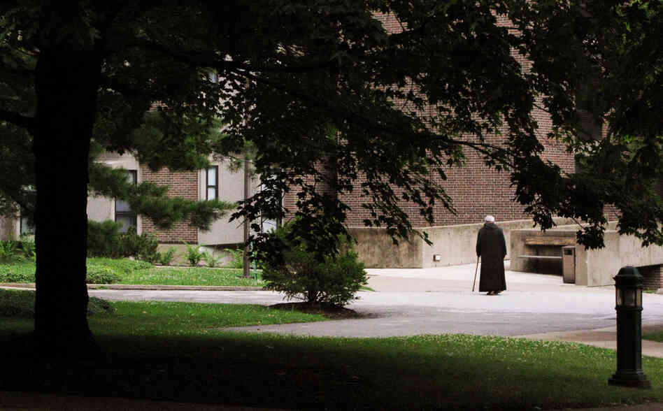 A monk walks with a cane outside the monastery at the Saint Vincent Archabbey.
