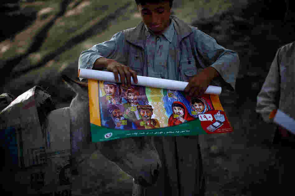 Boys from Quali Kuana helped carry the election materials with their donkeys. They roll up free posters from the U.N. — cartoons showing people how to vote.