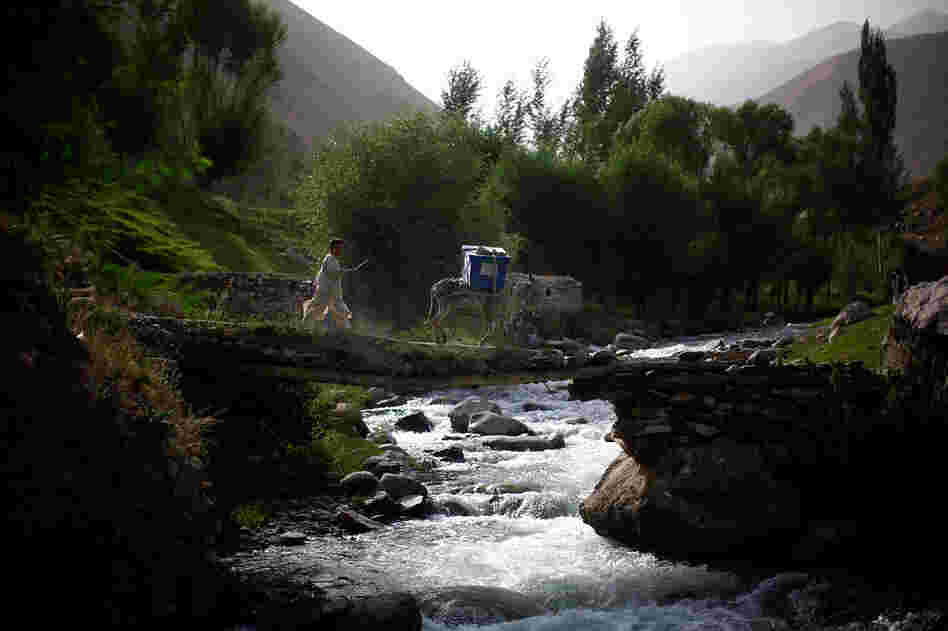 A boy and his donkey carry unused ballots across a stream while on their way to the village of Quali Kuana in the Yangam district.