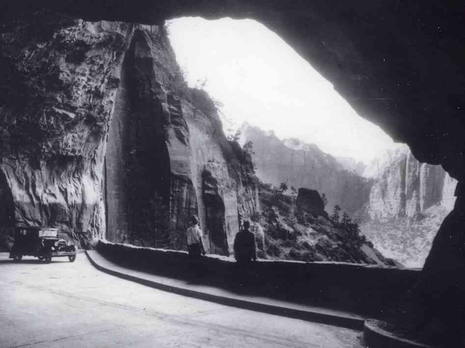 In the early days of Zion Tunnel, drivers could park at vast "windows" blasted in the canyon walls and gaze out at the steep red rock cliffs of Zion National Park. Credit:  Utah State Historical Society