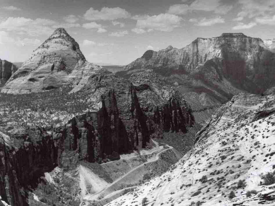 The Zion Tunnel approach road in the late 1920s is pictured here. The tunnel begins in the canyon wall near the left center of the image and stays just inside the canyon wall for the extent of its one-mile length. Credit: National Park Service