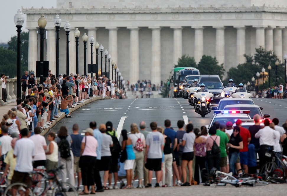 Spectators watch the motorcade for Kennedy cross Memorial Bridge on its way to Arlington National Cemetery. The Lincoln Memorial is in the background. 
