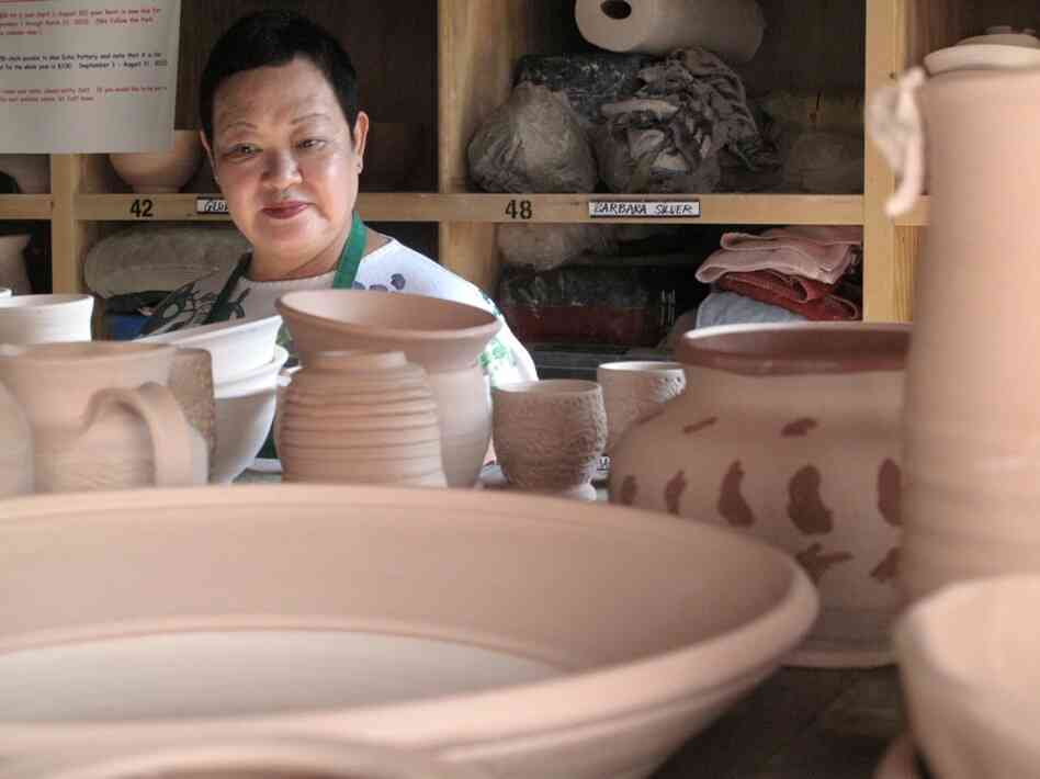 Shinko looks for her own pieces, among the dried pots waiting to be glazed.