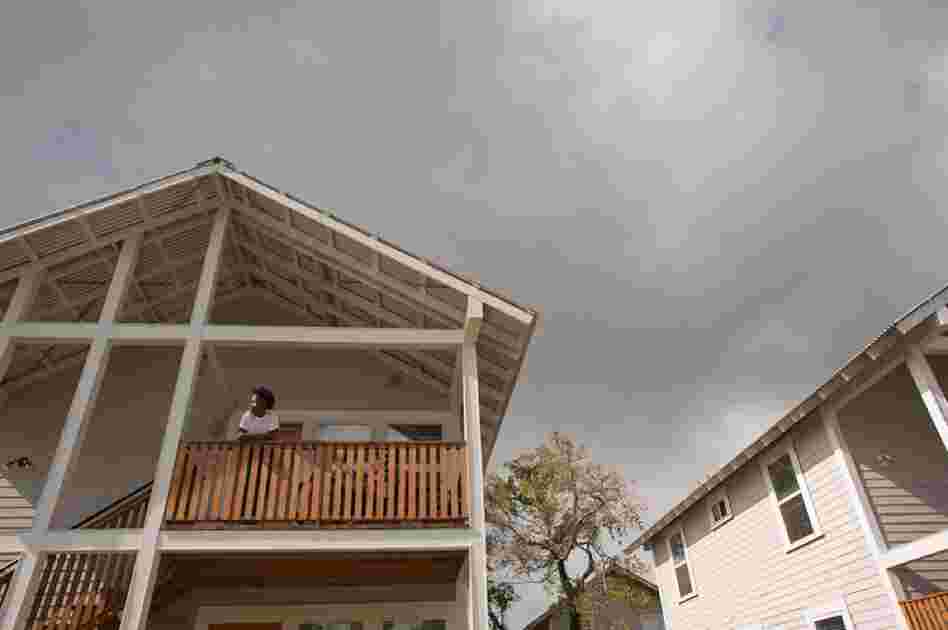 LaToya "Journey" Allen stands on the porch of the new duplex home she rents in the Third Ward.  Hoping to keep upscale developers away, local leaders bought land and built new rental homes like this one instead.