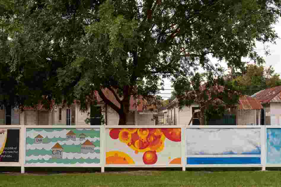 A mural proclaiming the need for rebuilding the city stands in front of a series of shotgun houses in the Third Ward.