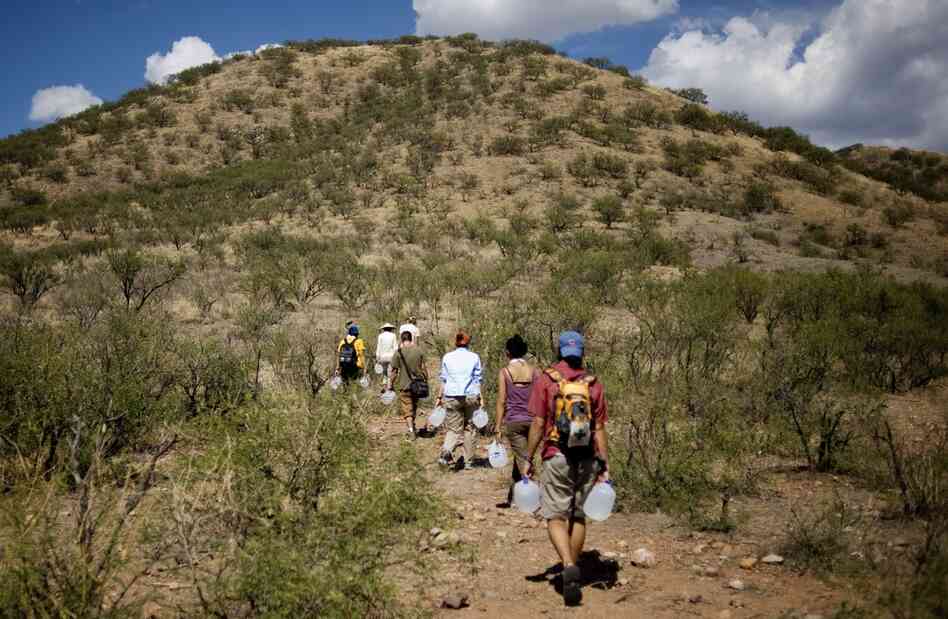 Volunteers from the humanitarian aid group No More Deaths carry jugs of water to a popular crossing path in Chiminea Canyon outside Arivaca, Ariz., on July 21. The group drops off water and gives medical attention to migrants trying to cross from Mexico through the desert to the United States.