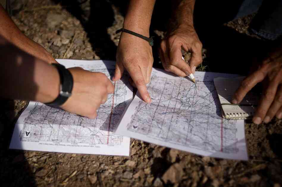 No More Deaths volunteers look at trail maps to decide where a water drop patrol will take place outside Arivaca, Ariz. Members of the group have spent years walking the trails in the Arivaca region to track migrant crossing patterns.
