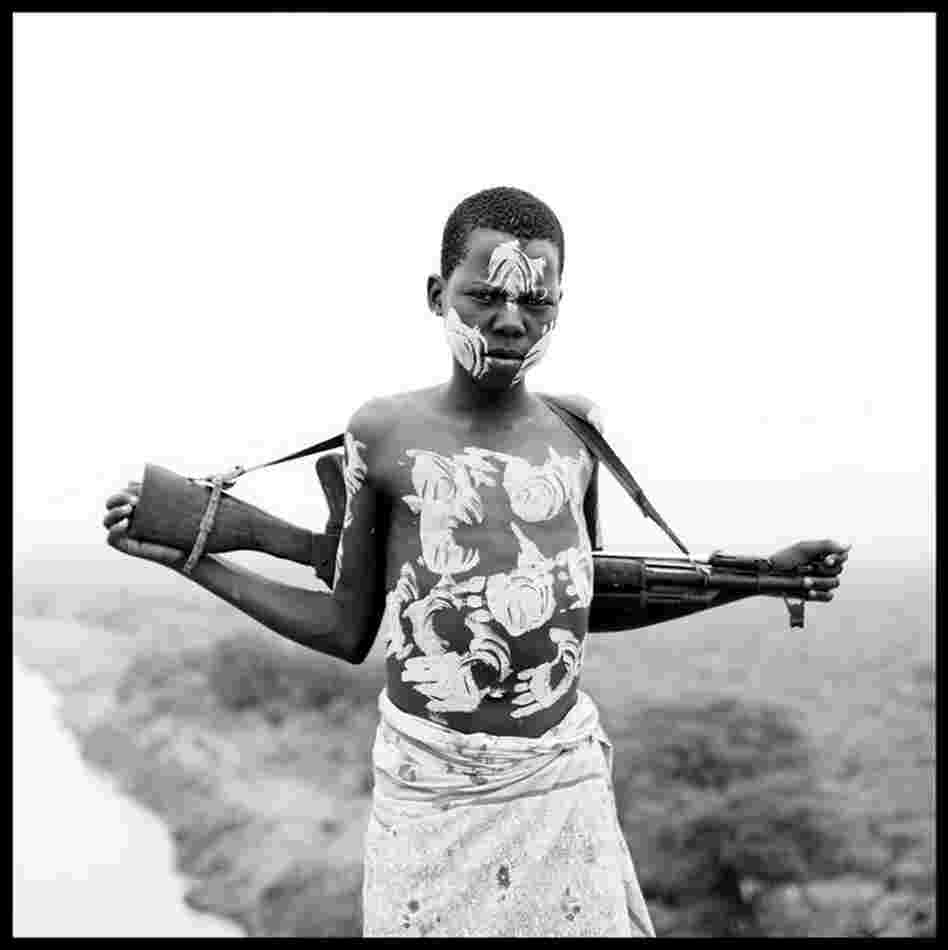 "A young boy holds a rifle on his back after decorating his body with white paint overlooking the Omo River in remote Ethiopia." 