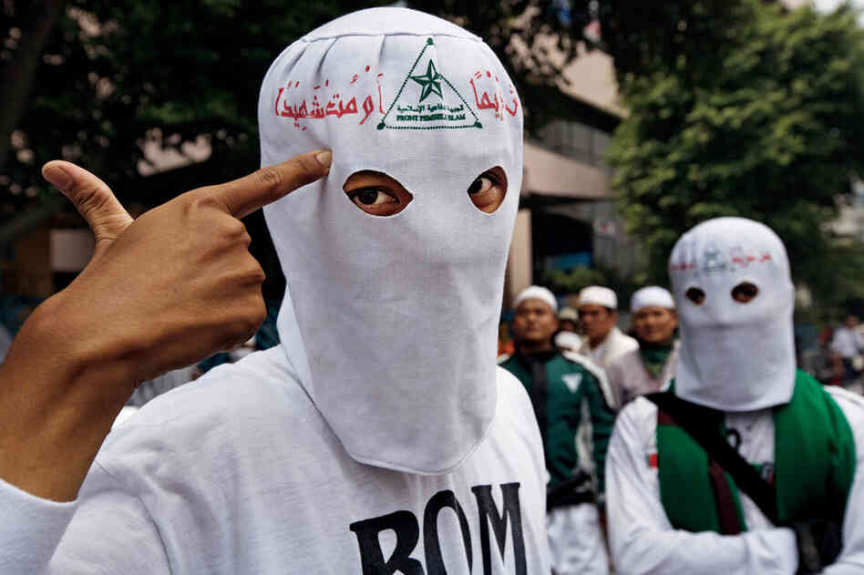 The red-letter motto on the hoods of Front Pembela Islam members reads, "Live respected or die as a martyr."