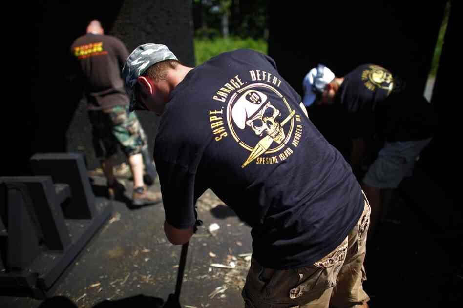 An explosives team sweeps up after a blast shattered a wooden bench into unrecognizable splinters.