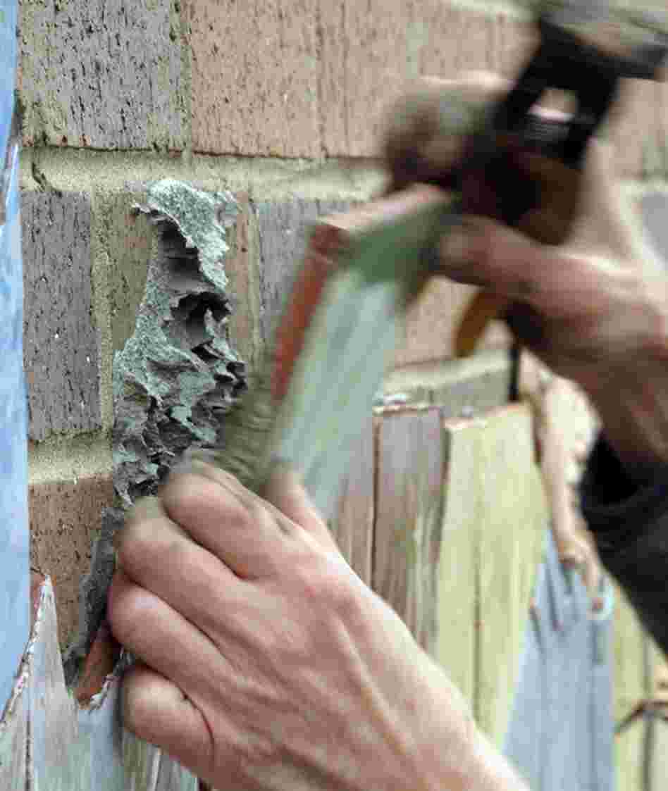 Judith uses a special wrench to fine-tune the cuts and then uses mortar to affix the tile to the wall.