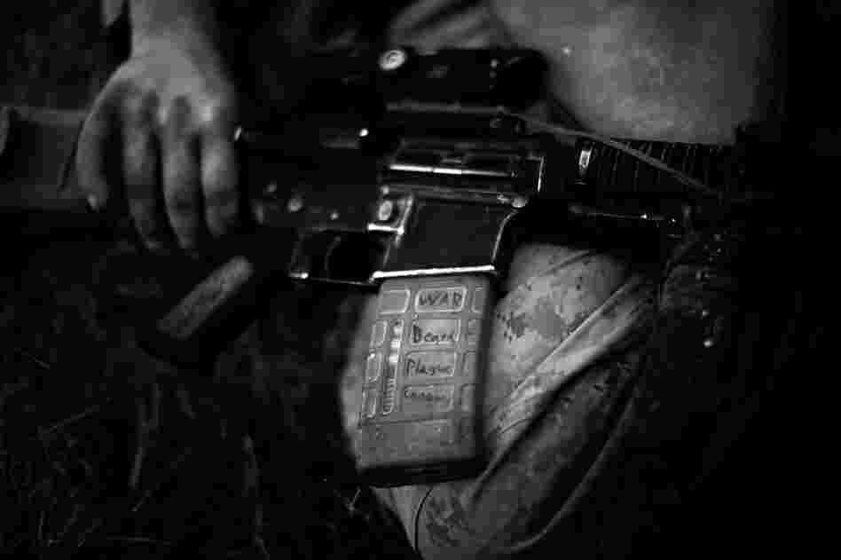 A Marine holds an M-16 rifle marked with words symbolizing the Four Horsemen of the Apocalypse from the Book of Revelation. He says the words keep him safe.