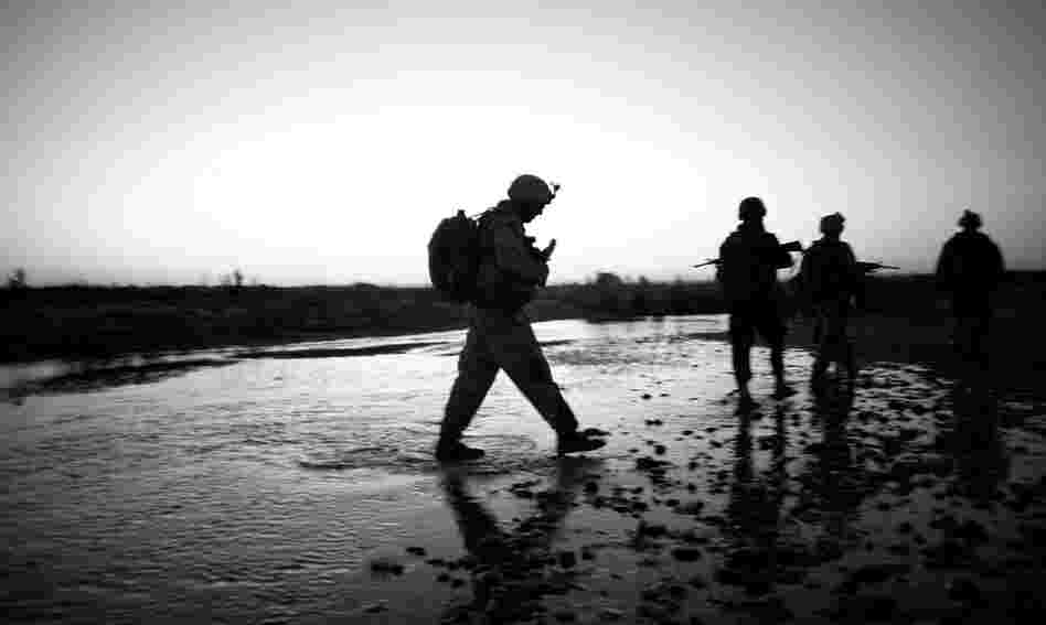 The Marines cross a stream during a dawn patrol through the farm fields of Helmand River valley.