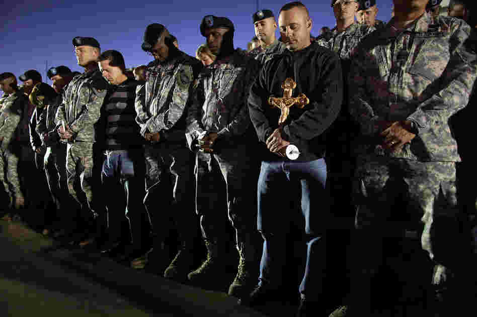 Soldiers bow their heads in prayer during a vigil at Fort Hood on Friday. 