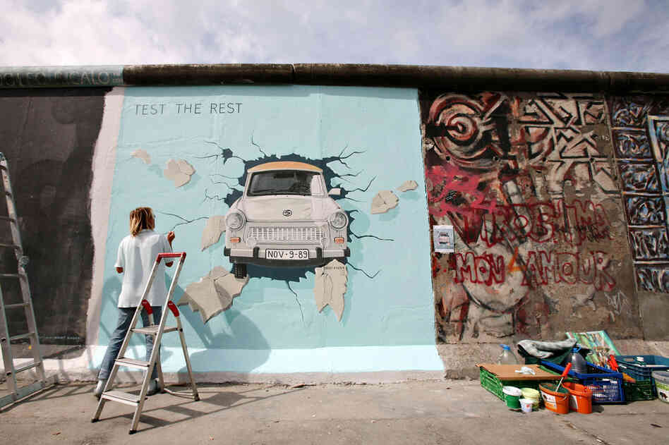 Birgit Kinder works on her painting Trabi on a portion of the Berlin Wall known as the East Side Gallery, on July 8, 2009.  Ninety-one international artists gathered to repaint their original creations on the concrete slabs. 