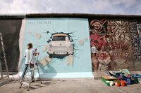 Birgit Kinder works on her painting <i>Trabi</i> on a portion of the Berlin Wall known as the East Side Gallery, on July 8, 2009. Ninety-one international artists gathered to repaint their original creations on the concrete slabs.