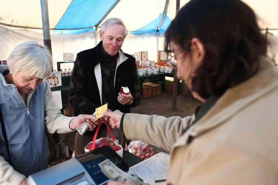 Brenda Bailey Collins (right) helps Jan and Ed Jenik purchase apples and cider at the farm stand at Poverty Lane. The stand is open from Labor Day weekend through Halloween.