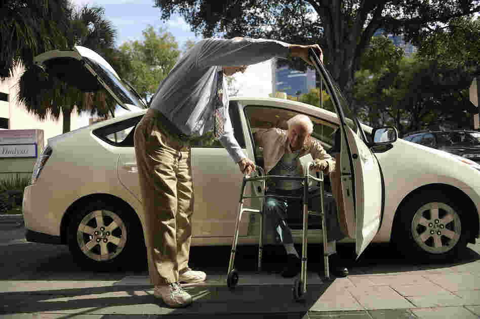 Seymour assists Gruner as he gets out of the car at his doctor's office in Winter Park, Fla. ITN offers door "through" door service, which guarantees the driver will pick up passengers inside their homes and escort them into their destinations.
