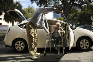 Seymour assists Gruner as he gets out of the car at his doctor's office in Winter Park, Fla. ITN offers door "through" door service, which guarantees the driver will pick up passengers inside their homes and escort them into their destinations.