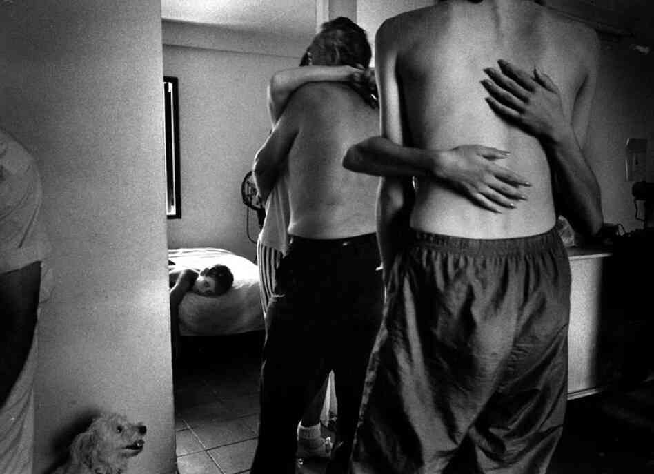 A dog observes slow-dancing couples as a boy sleeps at a private party in Havana, 1995.