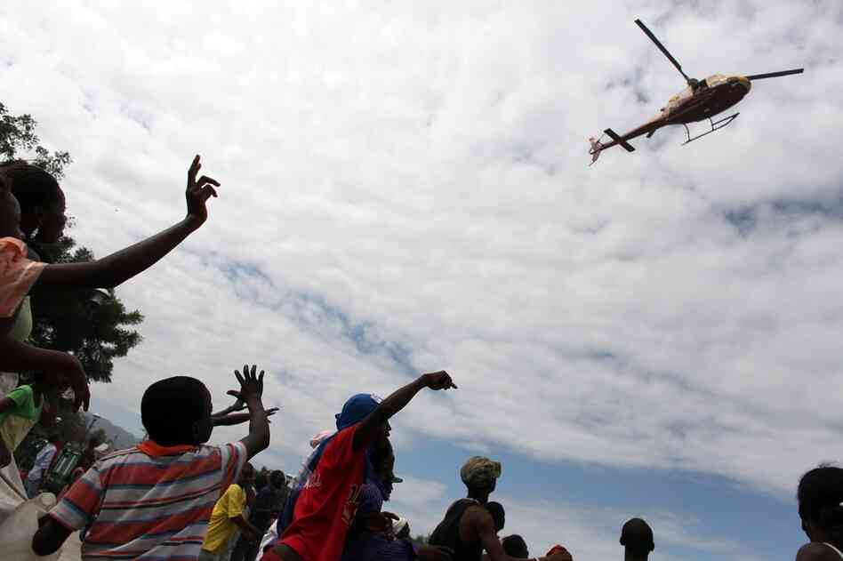 People wave at a helicopter in the center of Port-au-Prince. Aid efforts are slow to reach the Haitian capital. 