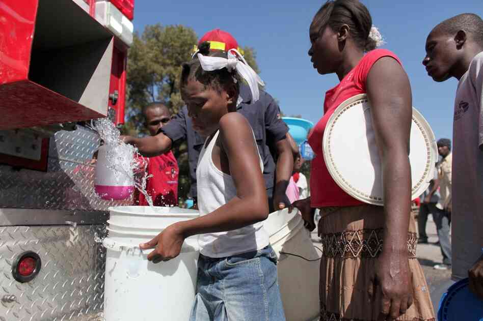 People line up to receive water, an in-demand commodity, from a firetruck in Port-au-Prince.  