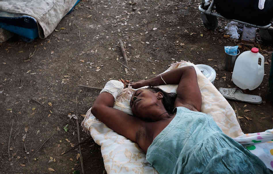A woman who lost a hand lies on the ground outside a makeshift recovery ward in Port-au-Prince Friday. 
