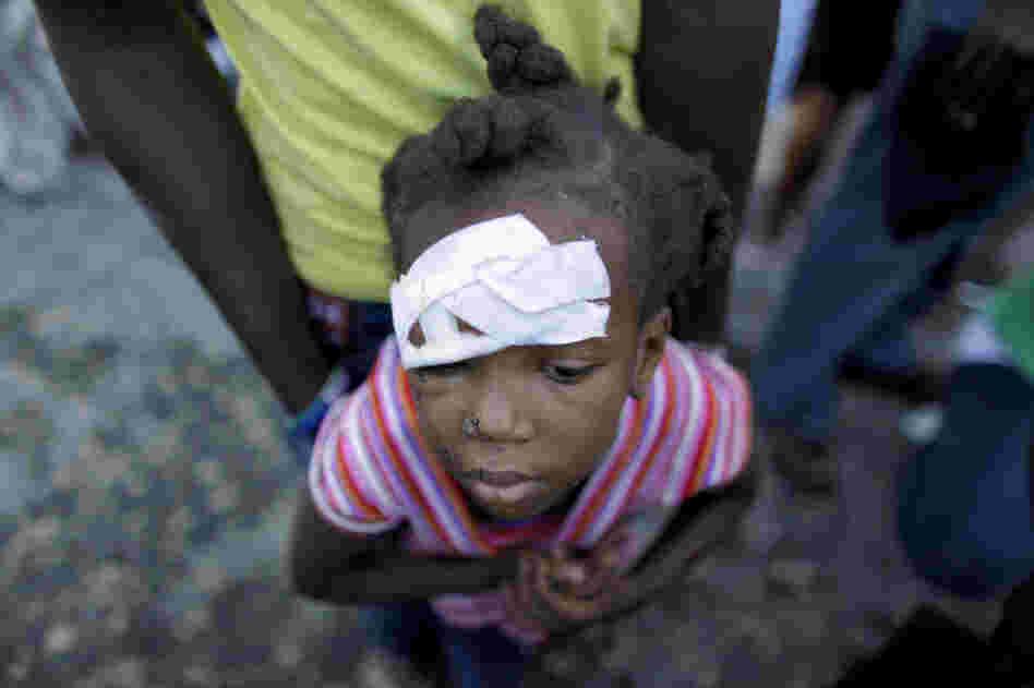 An injured child waits for medical attention near a damaged hospital in Carrefour, on the outskirts of Port-au-Prince, Friday. 
