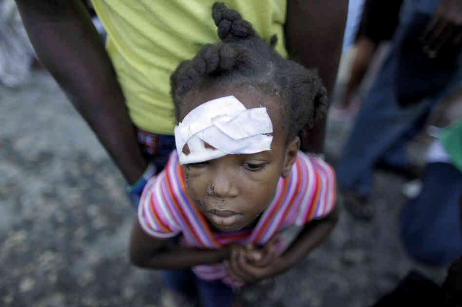 An injured child waits for medical attention near a damaged hospital in Carrefour, on the outskirts of Port-au-Prince, Friday. 