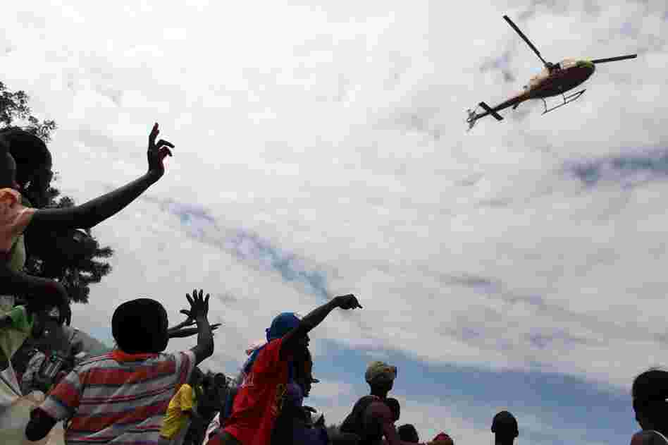 People wave at a helicopter in the center of Port-au-Prince. Aid efforts are slow to reach the Haitian capital. 