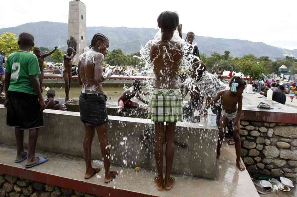 Earthquake survivors use water from a fountain to bathe in the central public garden of Port-au-Prince. 