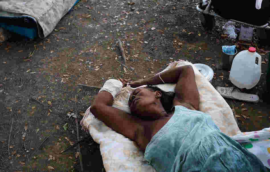 A woman who lost a hand lies on the ground outside a makeshift recovery ward in Port-au-Prince Friday. 