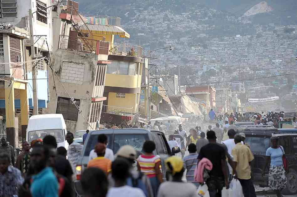 Haitians walk though streets filled with rubble and bodies. 