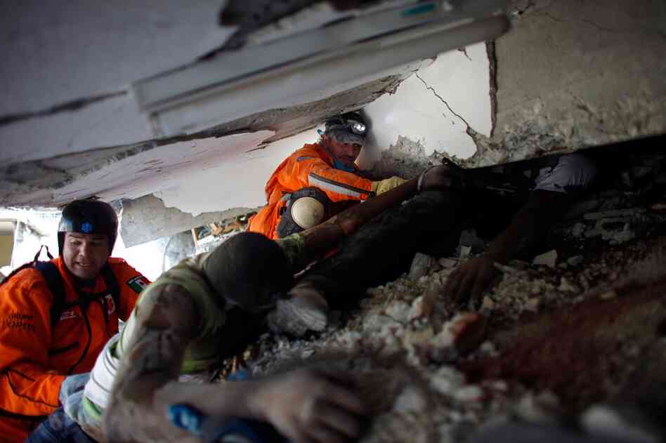 Mexican rescue workers try to extract the bodies of victims crushed during the collapse of the St. Gerard school outside of Port-au-Prince.