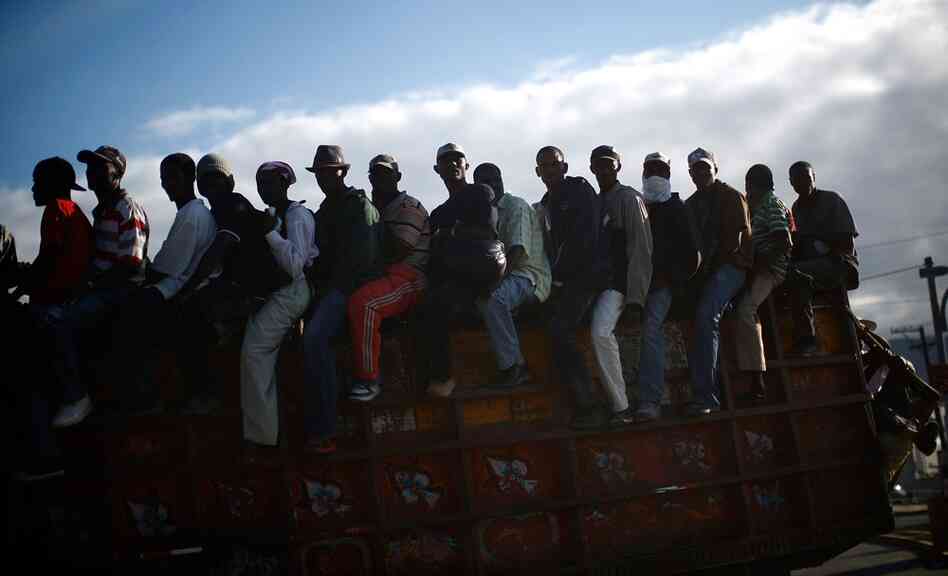 Men ride on the back of a truck leaving Port-au-Prince. U.N. officials warned that Haitians are becoming increasingly fed up with the pace of aid.