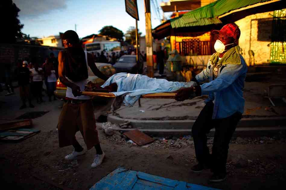 Haitian men carry the body of a child to a dump truck near downtown Port-au-Prince on Thursday.