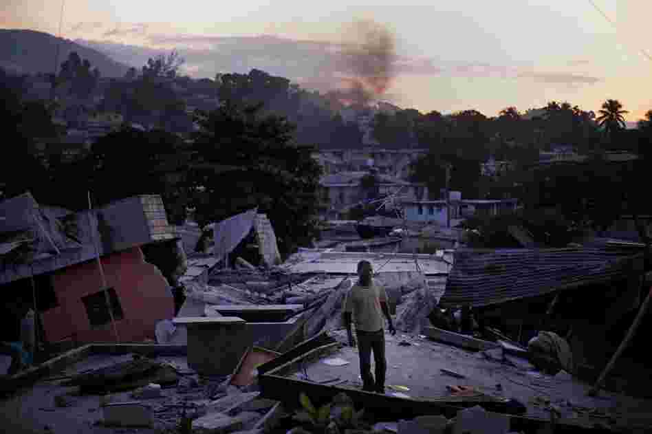 A man stands on a rooftop yelling out for any sign of his missing relatives Friday in a devastated hillside neighborhood near downtown Port-au-Prince.
